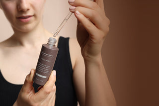 Woman experimenting with a brown skincare bottle on a brown background