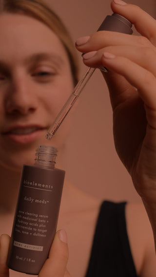 Woman experimenting with a brown skincare bottle on a brown background