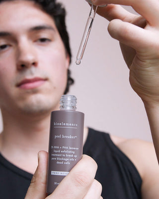 Man experimenting a brown bottle of the peel breaker Bioelements skincare product.