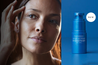 Woman touching her face with a blue skincare bottle labeled 'new' on a blue background