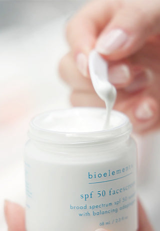 Bioelements sunscreen jar with a close-up of the cream being applied.