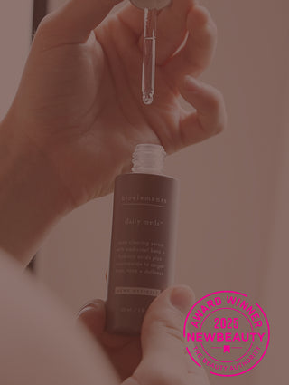 A woman hand experimenting a brown skincare product bottle from bioelements with a New Beauty 2025 Award Winner stamp.